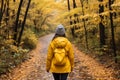 Serene unrecognizable woman walking on autumn forest path in the woods with vibrant fall foliage Royalty Free Stock Photo