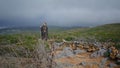 Serene woman hiking mountains at overcast sky. Trail tourist walking green hill