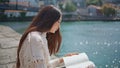 Serene woman looking book turning pages beautiful river promenade. Lady reading Royalty Free Stock Photo