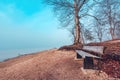 Serenity of Bohinj Lake on a foggy morning with empty wooden bench on shoreline