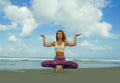 Young attractive and athletic woman in balance yoga posture at beautiful beach doing relaxation and meditation exercise under a