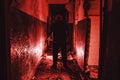 Serial killer silhouette with knife in hand in red corridor. Crime scene and trash horror maniac