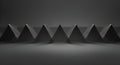 A series of black pyramidal shapes are aligned in a uniform row, creating a sharp, angular pattern against a dark gray background. Royalty Free Stock Photo