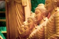 Series of Buddha statues. Face in the foreground, yellow gold sculptures. Royalty Free Stock Photo