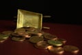 A series of coins falling from a golden vintage wheelbarrow on dark background