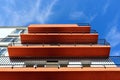 a series of red textured stucco balcony slabs. steel picket railing. perspective view. blue sky