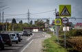 A series of road signs stands on a busy highway on a day