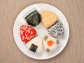 A series of shots of onigiri of various shapes and fillings on a plate. Top view. Japanese rice ball