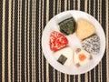 A series of shots of onigiri of various shapes and fillings on a plate. Top view. Japanese rice ball