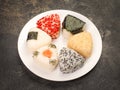 A series of shots of onigiri of various shapes and fillings on a plate. Top view. Japanese rice ball