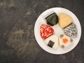 A series of shots of onigiri of various shapes and fillings on a plate. Top view. Japanese rice ball