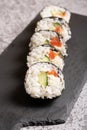 A series of sushi laid out on a black slate board. Focus on the first sushi