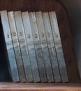 Eight volumes of old dusty books on bookshelf Royalty Free Stock Photo