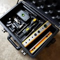 A series of tools for alignment and leveling displayed in a neat organized toolbox on a concrete floor