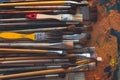 Series of wooden different size paintbrushes lying on palette with old oil paint cracked texture in art studio, top view Royalty Free Stock Photo