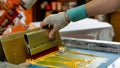 Serigraph printing production. silk screen textile printery. male hand with a squeegee. creating print on t-shirt in workshop