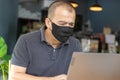 Serious adult Asian businessman with face mask feels stressed, worried about his job work while using computer laptop when home Royalty Free Stock Photo