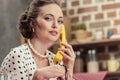 serious adult housewife talking by vintage wired phone and looking at camera Royalty Free Stock Photo