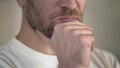 Serious adult man with beard rubbing chin, having doubts, thinking, close-up Royalty Free Stock Photo