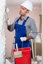 Serious adult man repairer working with roller in uniform, gloves and helmet