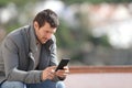 Serious adult man using smart phone in winter outdoors