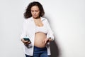 Serious adult pregnant woman with bare belly, holding smartphone and counting contractions, recording it in mobile app Royalty Free Stock Photo