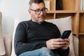 Serious adult unshaven man using cellphone while resting