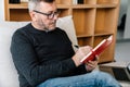 Serious adult unshaven man writing down notes while working with laptop