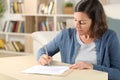 Serious adult woman signing document at home Royalty Free Stock Photo