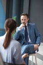 Serious affluent businessman listening to journalist asking him questions