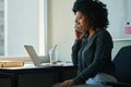 Serious african american business woman calling by phone, using laptop Royalty Free Stock Photo