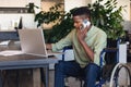 Serious african american businessman with disability talking on smart phone and using laptop Royalty Free Stock Photo