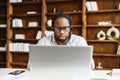 Serious african-american businessman in eyeglasses sitting in front of the laptop Royalty Free Stock Photo