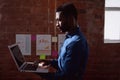 Serious african american businessman standing in office holding and using laptop Royalty Free Stock Photo