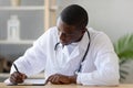 Serious African American doctor filling patient form document close up Royalty Free Stock Photo
