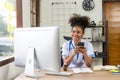 Serious African American doctor working in her office at clinic in white medical gown and stethoscope busy working on computer Royalty Free Stock Photo