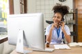 Serious African American doctor working in her office at clinic in white medical gown and stethoscope busy working on computer Royalty Free Stock Photo