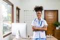Serious African American doctor working in her office at clinic in white medical gown and stethoscope busy working on computer Royalty Free Stock Photo