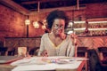 Serious African-American female thoroughly looking at papers in cafeteria