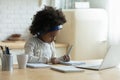 Serious African American little girl wearing headphones writing notes Royalty Free Stock Photo