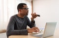 Serious African American Male Freelancer talking smartphone using voice recognition and working on laptop computer Royalty Free Stock Photo