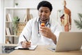 Pharmacist with pill bottle seating behind laptop in clinic Royalty Free Stock Photo