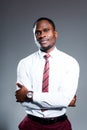 Serious african american man in shirt and tie folds his arms over his chest and stands against gray background Royalty Free Stock Photo