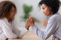 Serious african american mom and teen daughter arm wrestling