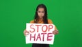 Serious African American teen girl raising Stop hate banner looking at camera shaking head no on green screen. Portrait