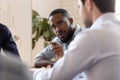 Serious african boss talking to diverse employees at group meeting