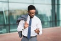 Serious African Businessman Texting Standing With Travel Suticase Near Airport