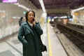 Serious african businesswoman talk on phone call at subway platform while waiting for metro train Royalty Free Stock Photo