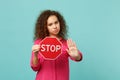 Serious african girl in pink casual clothes holding text board STOP showing stop gesture with palm isolated on blue