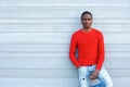 Serious african man with red sweater leaning against wall Royalty Free Stock Photo